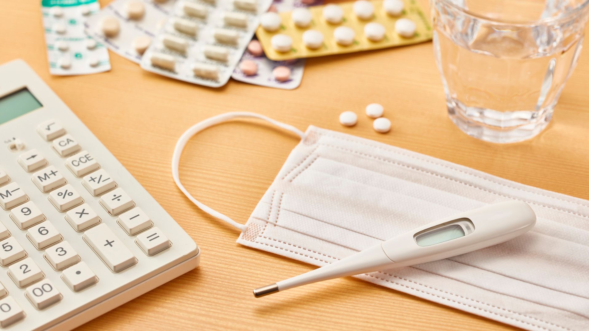 Medication, a thermometer, and a glass of water, representing STI treatment