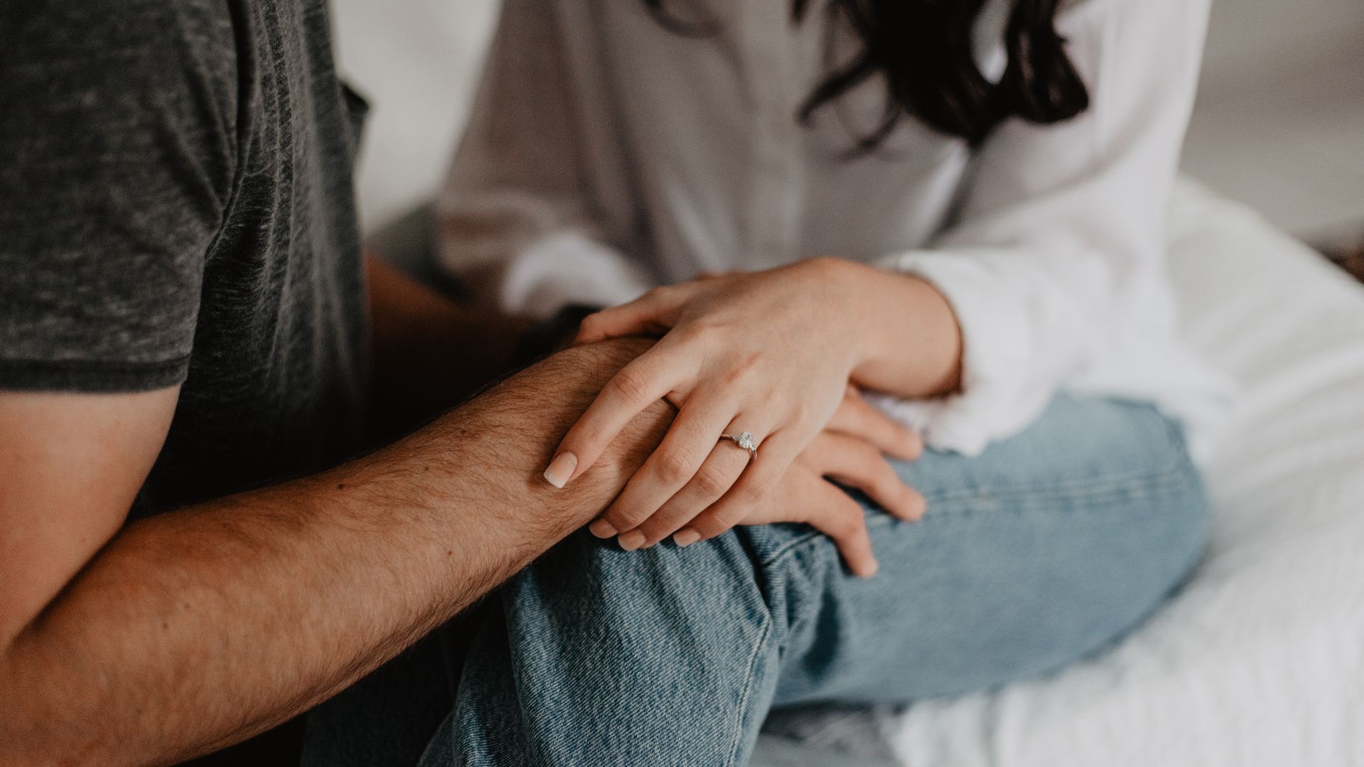 A couple sitting close together with their hands resting on each other, representing deciding when to test after sex